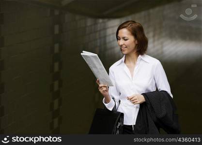 Close-up of a businesswoman reading a newspaper and smiling