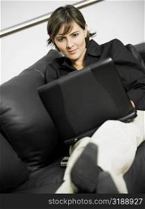 Close-up of a businesswoman reclining on a couch and using a laptop