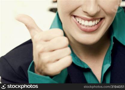 Close-up of a businesswoman showing thumbs up sign and smiling