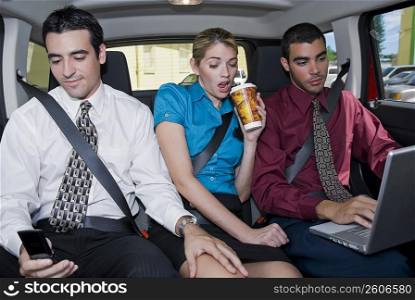 Close-up of a businesswoman sitting between two businessmen in a car
