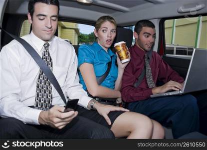 Close-up of a businesswoman sitting between two businessmen in a car