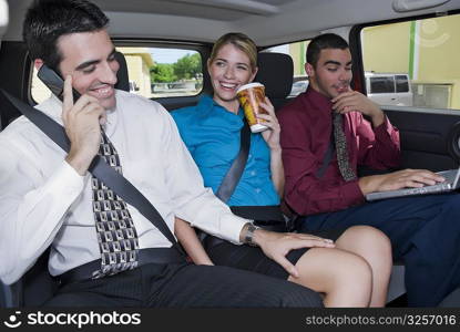 Close-up of a businesswoman sitting between two businessmen in a car and smiling