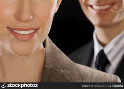 Close-up of a businesswoman smiling with a businessman behind her
