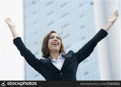 Close-up of a businesswoman smiling with her arms raised