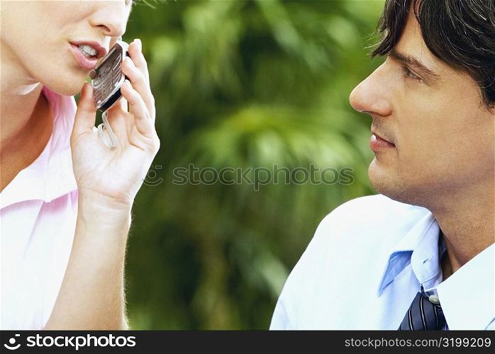 Close-up of a businesswoman talking on a mobile phone and a businessman looking at her