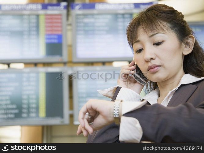 Close-up of a businesswoman talking on a mobile phone and checking the time