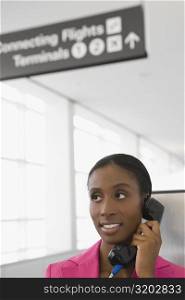 Close-up of a businesswoman talking on a pay phone and smiling