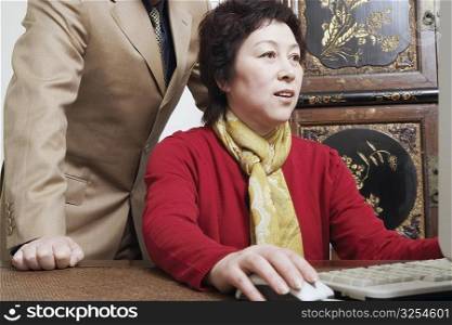 Close-up of a businesswoman using a computer with a businessman standing behind her