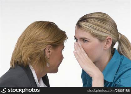 Close-up of a businesswoman whispering into another businesswoman&acute;s ear