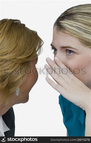 Close-up of a businesswoman whispering into another businesswoman&acute;s ear