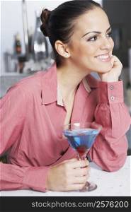 Close-up of a businesswoman with a glass of cocktail smiling in a bar