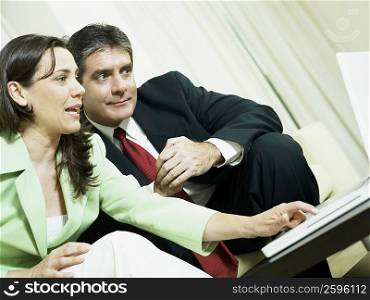 Close-up of a businesswoman working on a laptop and a businessman sitting beside her