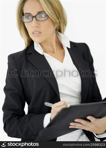 Close-up of a businesswoman writing on a file