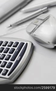 Close-up of a calculator and a computer mouse with a ballpoint pen