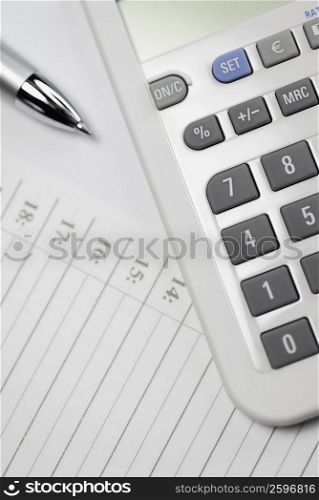 Close-up of a calculator and a pen