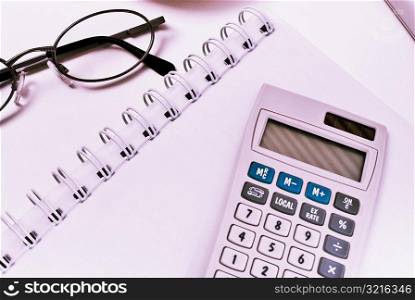 Close-up of a calculator and eyeglasses on a spiral notebook