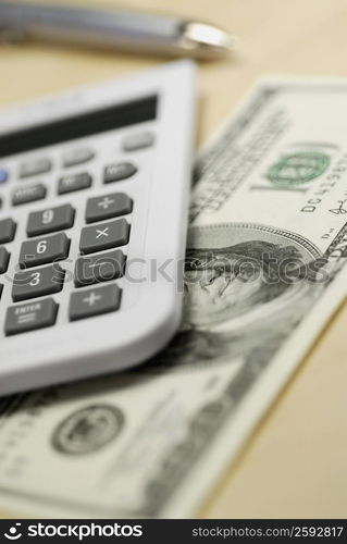 Close-up of a calculator and one hundred dollar bill on the table