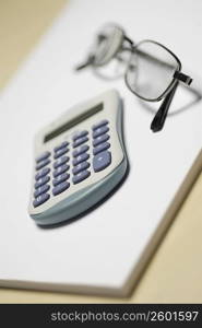 Close-up of a calculator with a pair of eyeglasses on a notepad