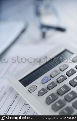 Close-up of a calculator with a pair of eyeglasses on documents