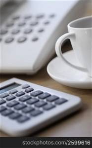 Close-up of a calculator with a tea cup