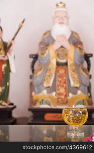 Close-up of a candle burning in front of a figurine of Confucius