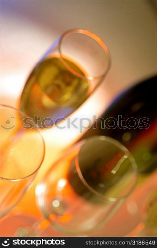 Close-up of a champagne bottle with three champagne flutes