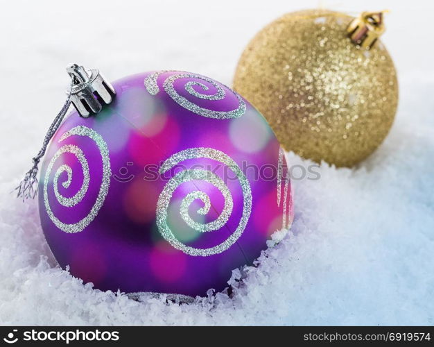 Close-up of a Christmas ball lying on the snow. Focus on the front ball