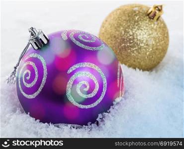 Close-up of a Christmas ball lying on the snow. Focus on the front ball