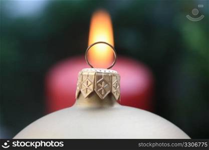 Close up of a christmas ball with a candle in the background