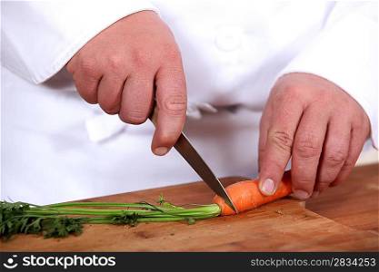 close-up of a cook slicing a carrot