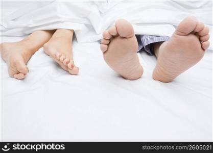 Close-up of a couple&acute;s feet on the bed