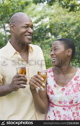 Close-up of a couple holding glasses of ice tea and smiling