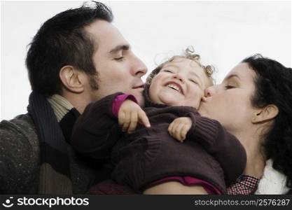 Close-up of a couple kissing their daughter