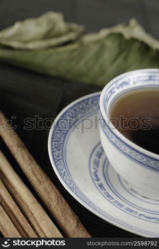 Close-up of a cup of coffee on a saucer with sticks beside it