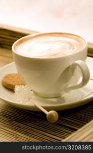 Close-up of a cup of coffee with sugar candy and a cookie