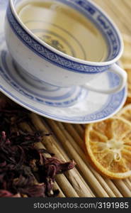 Close-up of a cup of herbal tea with dry herbal leaves