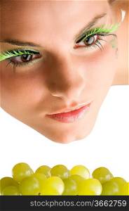 close up of a cute girl with artificial eyelashes and some green grape