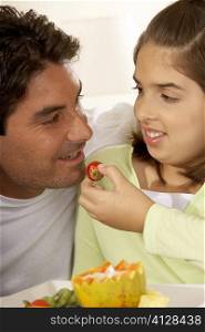 Close-up of a daughter feeding her father a strawberry