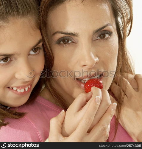 Close-up of a daughter feeding her mother a strawberry