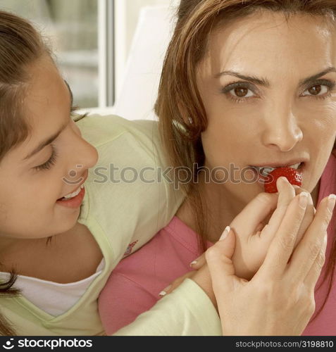 Close-up of a daughter feeding her mother a strawberry