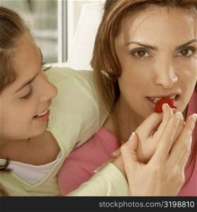 Close-up of a daughter feeding her mother a strawberry