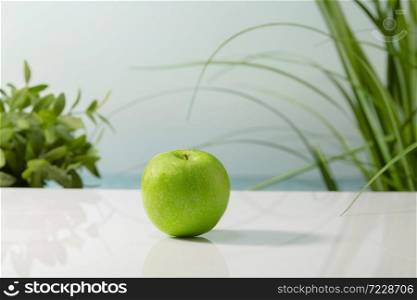 Close up of a delicious looking green apple on a table on an out of focus background. Healthy and vegan food concept.. a delicious looking green apple on a table on an out of focus background. Healthy and vegan food concept.