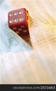 Close-up of a dice on a torn financial page