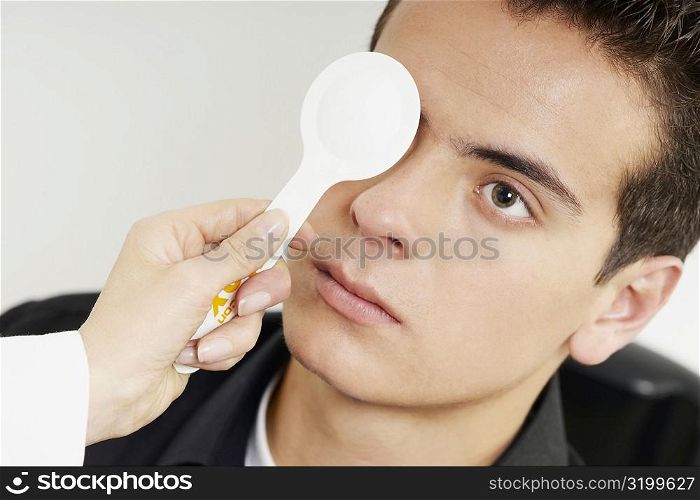 Close-up of a doctor&acute;s hand examining a young man&acute;s eye