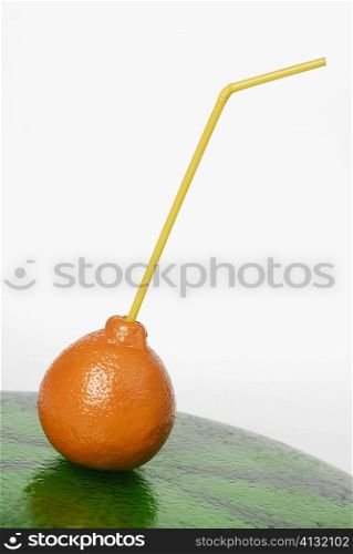 Close-up of a drinking straw inserted in an orange