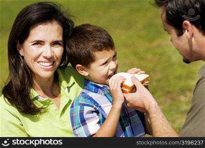 Close-up of a father feeding his son a sandwich