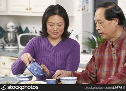 Close-up of a father looking at his daughter pouring tea