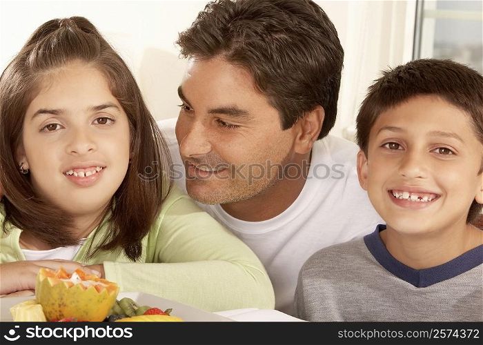 Close-up of a father with his son and his daughter smiling