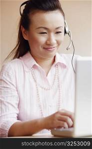 Close-up of a female customer service representative talking on a headset and using a laptop