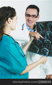 Close-up of a female doctor holding an X-Ray with a male doctor pointing at it